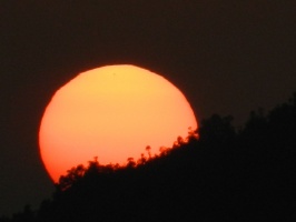 Setting sun behind distant mountain